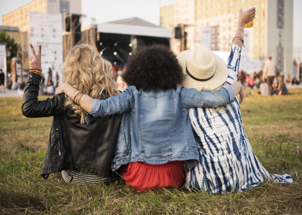 groupe-d-amis-vue-de-dos-assis-dans-l-herbe-a-un-festival-de-musique