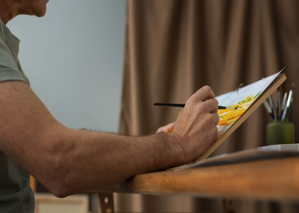 gros-plan-d-un-homme-qui-fait-de-la-peinture-sur-toile-sur-une-table