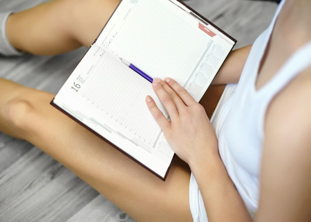 femme-assise-par-terre-agenda-sur-les-genoux
