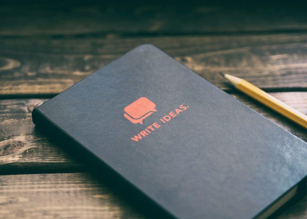 carnet-noir-avec-ecriture-rouge-dessus-pose-sur-une-table-en-bois