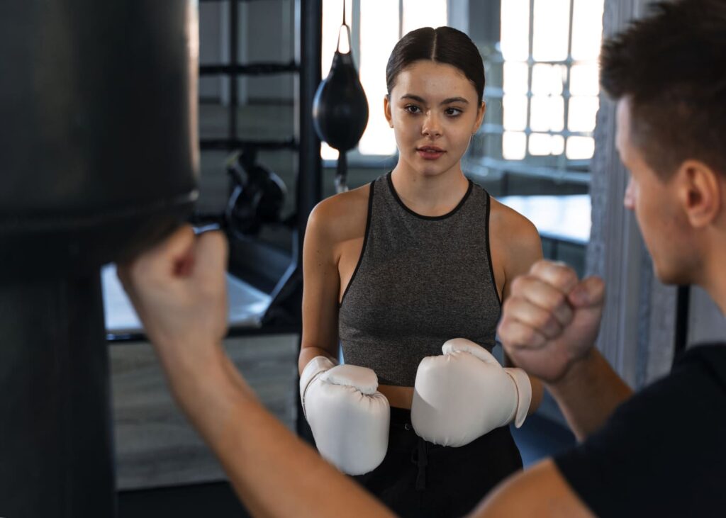 coach-de-boxe-qui-montre-des-tecniques-a-une-femme-qui-porte-des-gants-de-boxe