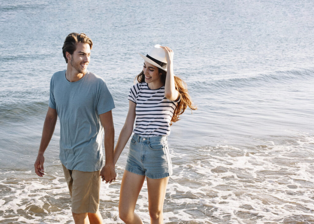 couple-souriant-qui-marche-main-dans-la-main-au-bord-de-la-mer