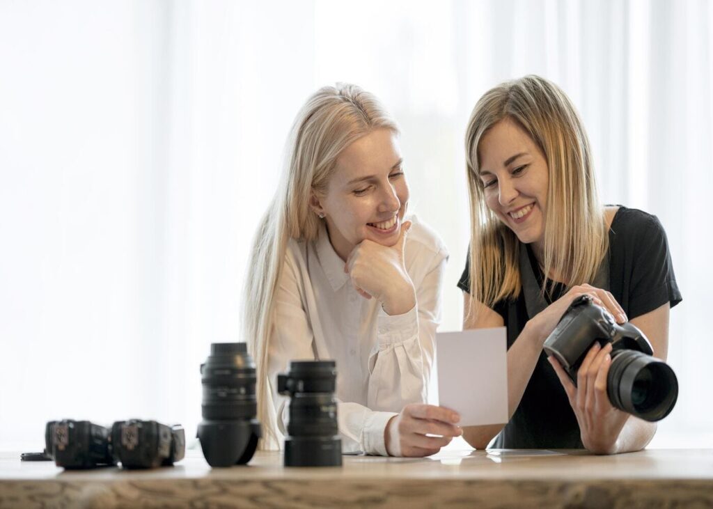deux-femmes-blondes-qui-regardent-une-photo-avec-plusieurs-objectifs-d-appareils-devant-elles