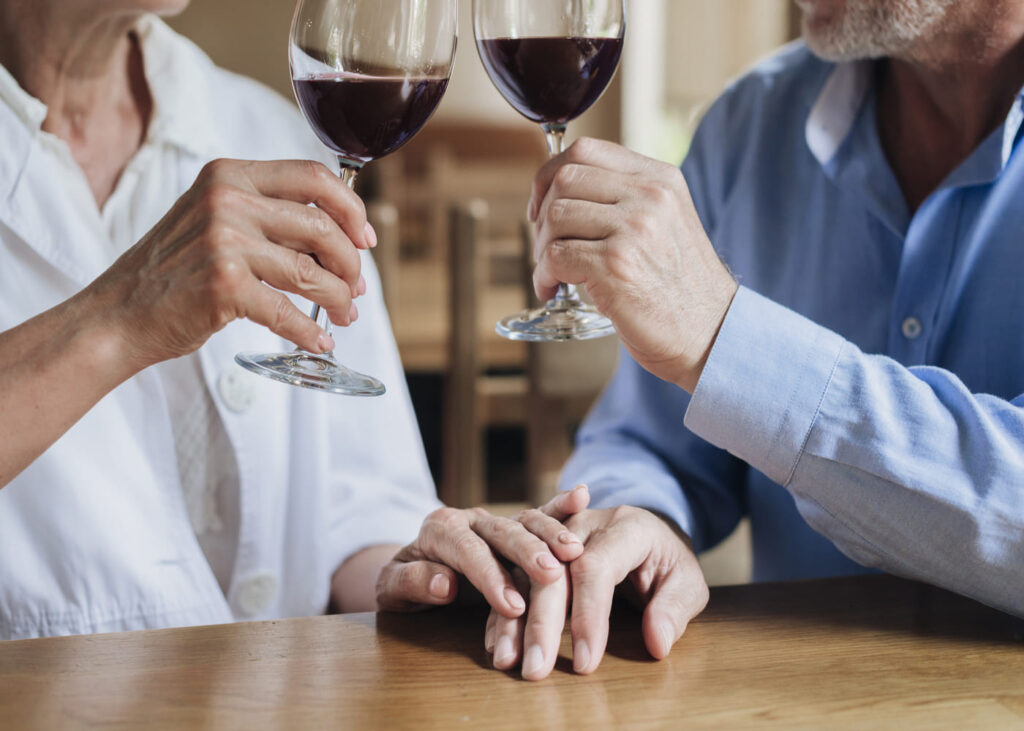 deux-personnes-en-train-de-trinquer-avc-un-verre-de-vin-rouge-a-la-main