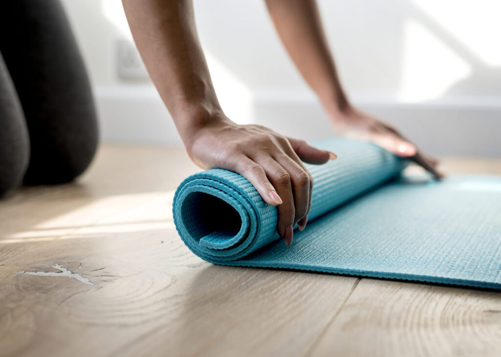 femme-a-genoux-qui-enroule-son-tapis-de-yoga