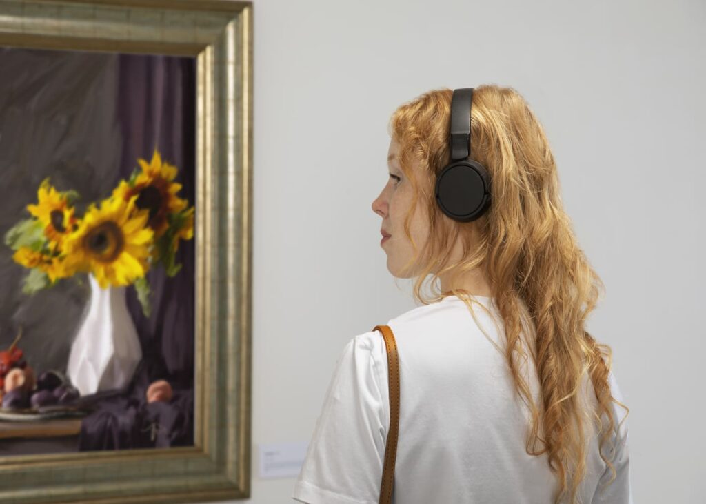 femme-avec-un-casque-sur-les-oreilles-qui-regardent-une-peinture-de-fleurs-dans-un-musee.jpg