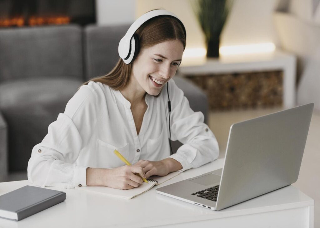 femme-avec-un-casque-sur-les-oreilles-qui-sourit-en-appel-visio-sur-son-ordinateur