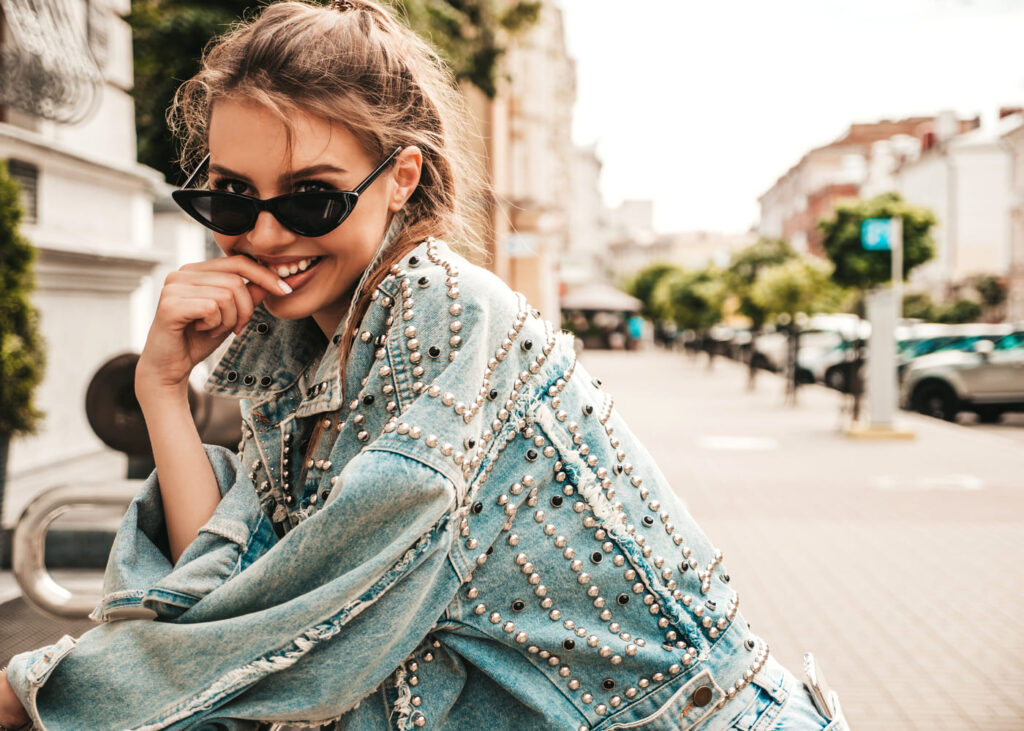 femme-blonde-qui-pose-en-souriant-avec-une-veste-en-jean