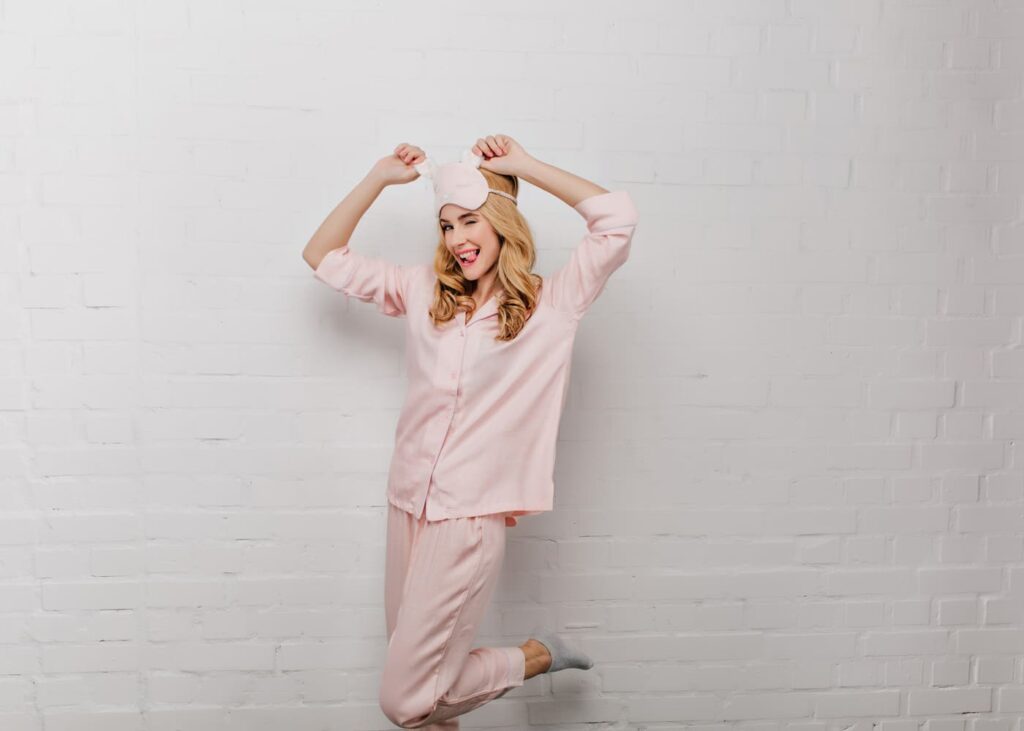 femme-en-pyjama-rose-avec-un-masque-de-sommeil-qui-tire-la-langue