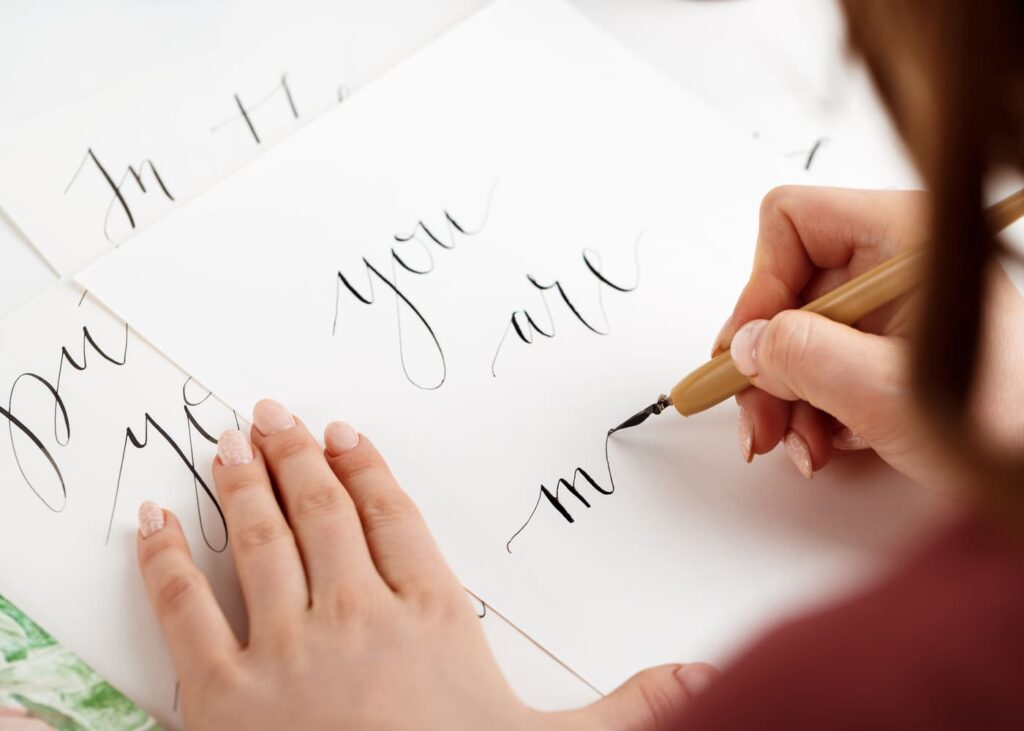 femme-qui-ecrit-sur-une-feuille-des-lettres-en-calligraphie