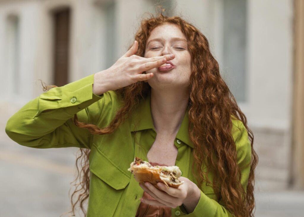 femme-qui-sourit-en-mangeant-un-sandwich