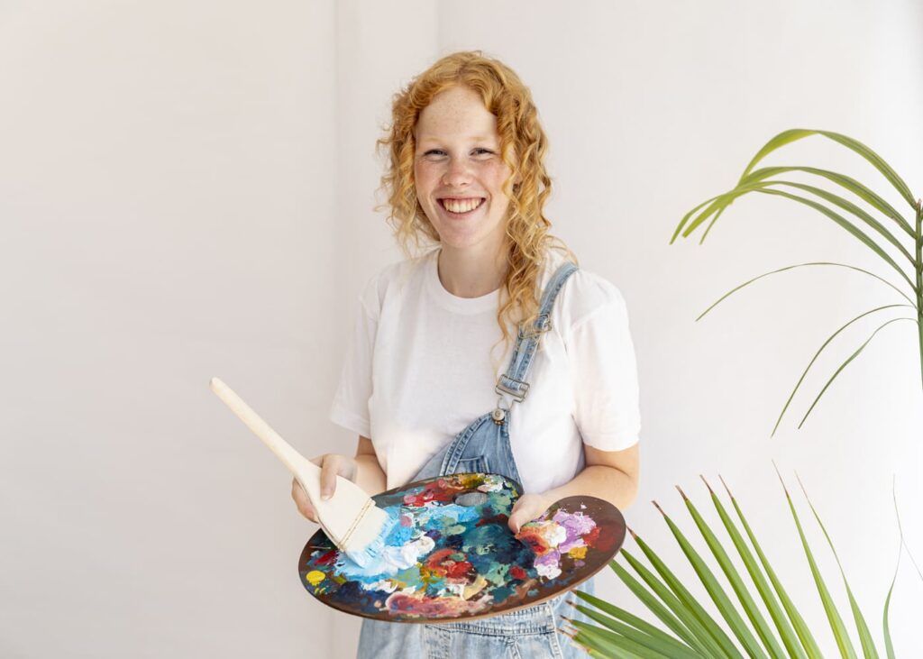 femme-qui-sourit-en-tenant-une-palette-de-peinture-dans-les-mains