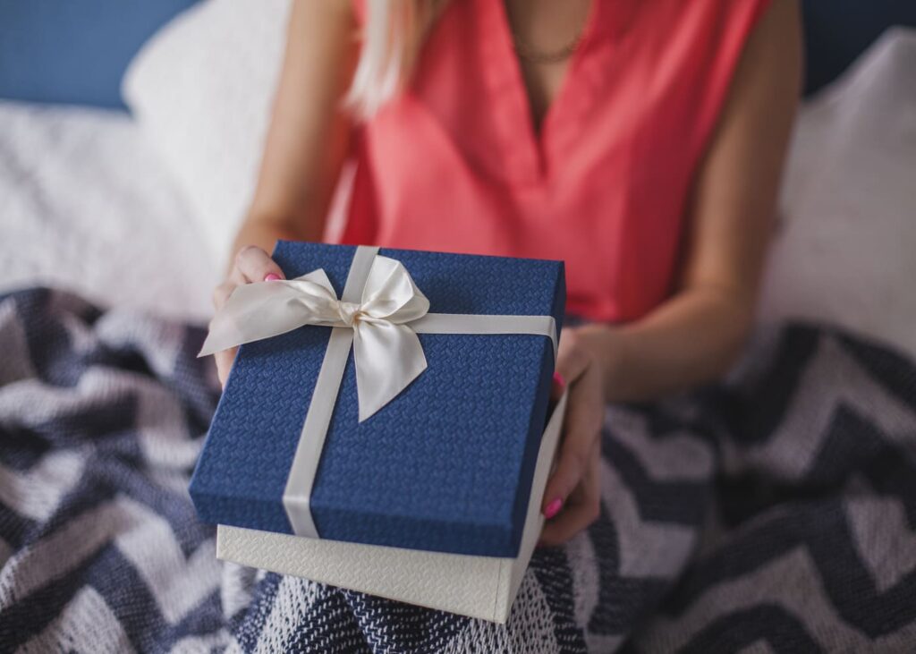 femme-qui-tient-un-cadeau-bleu-dans-les-mains