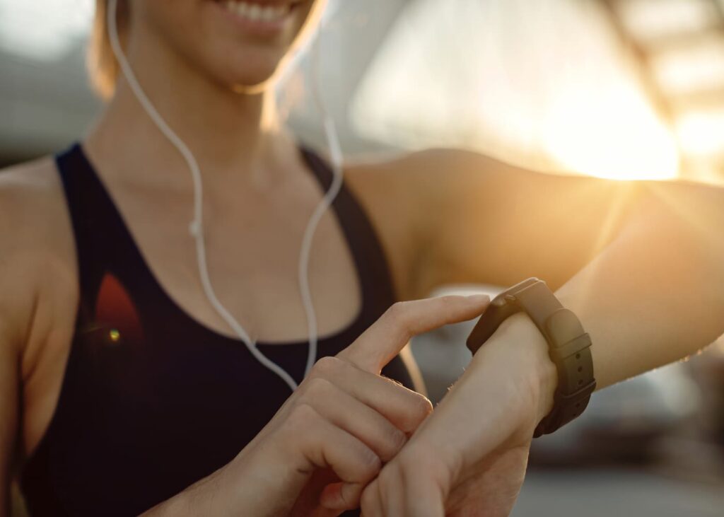femme-sportive-avec-des-ecouteurs-sui-touche-sa-montre-connectee
