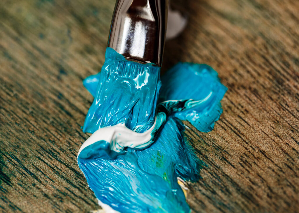 gros-plan-d-un-pinceau-avec-de-la-peinture-bleu-sur-une-table-en-bois