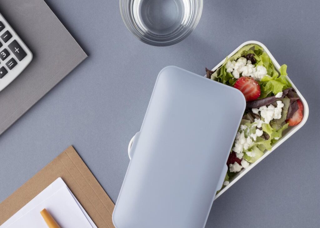 gros-plan-d-un-tupperware-rempli-de-nourriture-pose-sur-un-bureau-de-travail