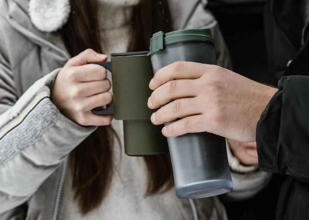 gros-plan-de-deux-personnes-qui-tiennent-chacun-un-mug-isotherme