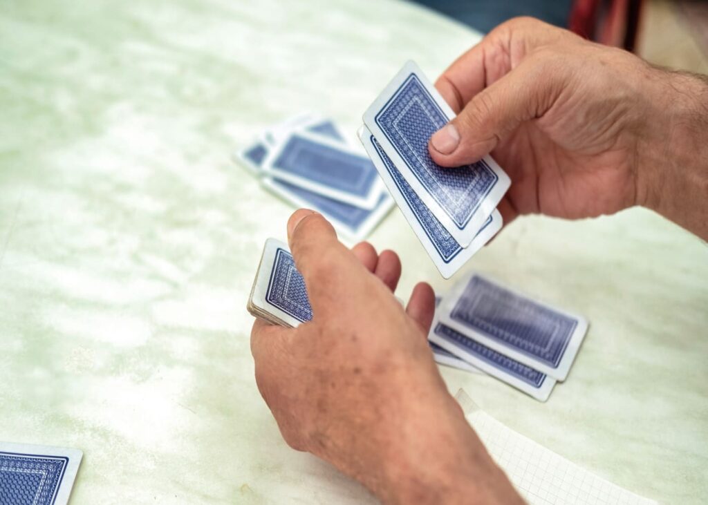 gros-plan-de-mains-d-homme-qui-joue-aux-cartes