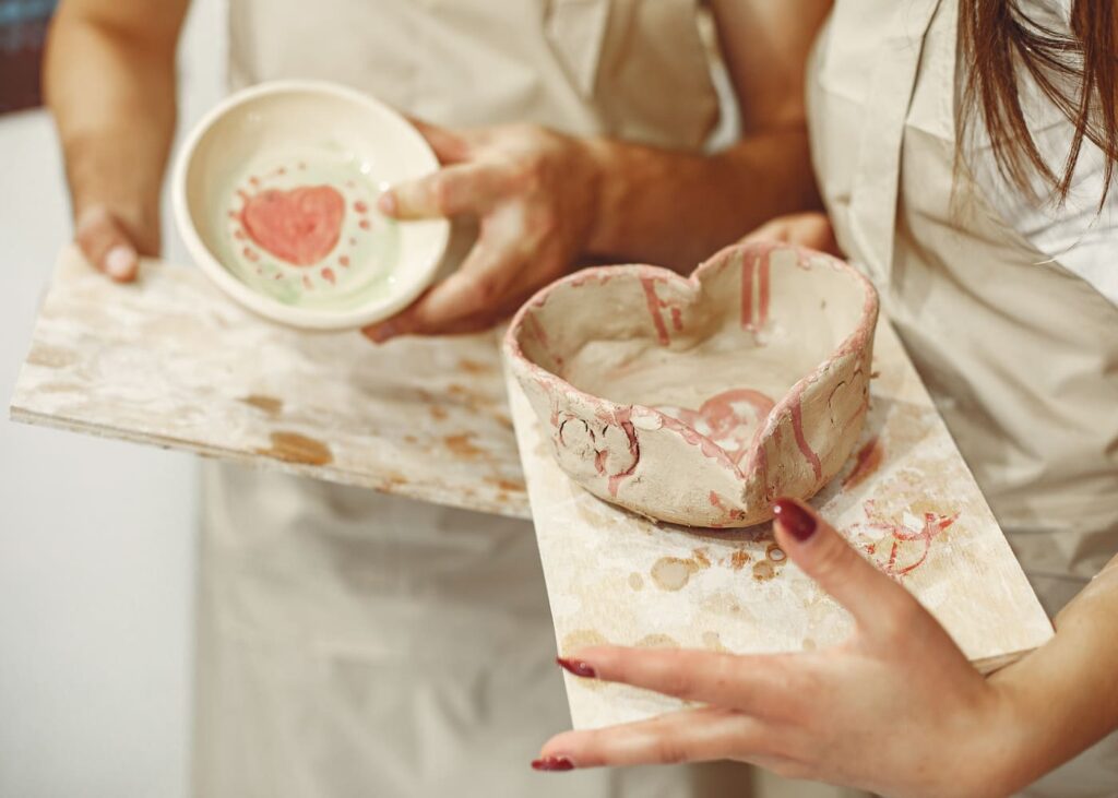gros-plan-sur-des-mains-de-femme-tenant-chacune-un-pot-peint-en-ceramique