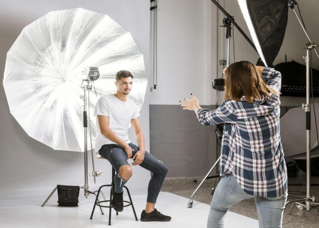 home-qui-prend-la-pose-sur-un-tabouret-devant-une-photographe-lors-d-un-shooting