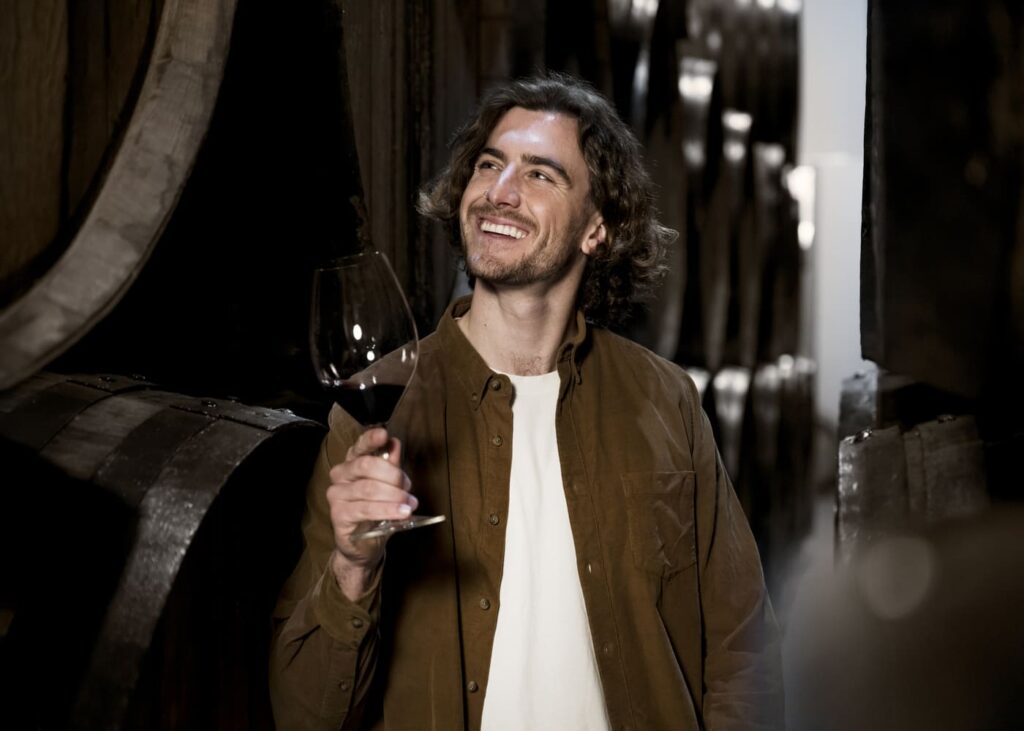 homme-qui-sourit-dans-une-cave-a-vins-un-verre-a-la-main