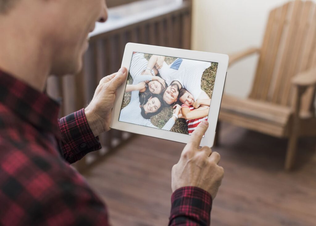 homme-qui-sourit-devant-une-photo-encadree-de-sa-famille