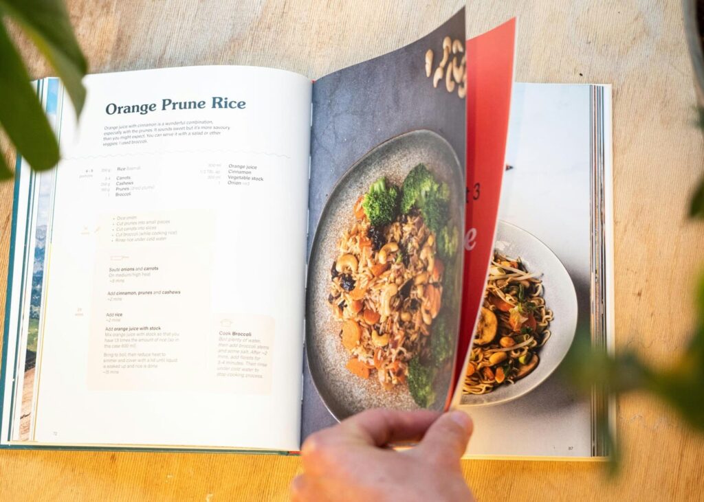 homme-qui-tourne-les-pages-d-un-livre-de-cuisine-pose-sur-une-table-en-bois