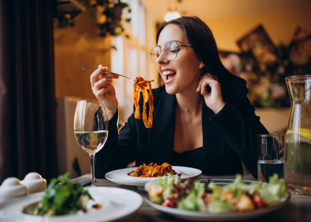 jeune-femme-avec-des-lunettes-qui-mange-des-pates-dans-un-restaurant