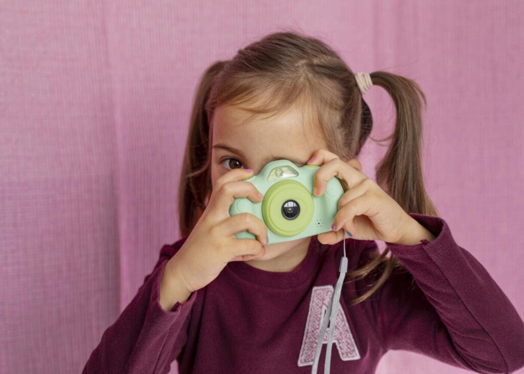 petite-fille-qui-joue-avec-un-appareil-photo-pour-enfants