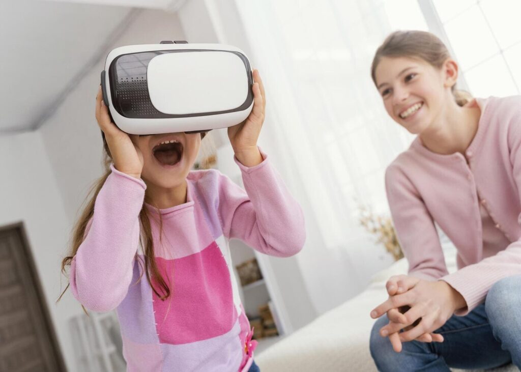 petite-fille-qui-joue-avec-un-casque-vr-sur-la-tete-avec-sa-grand-soeur-a-cote.jpg
