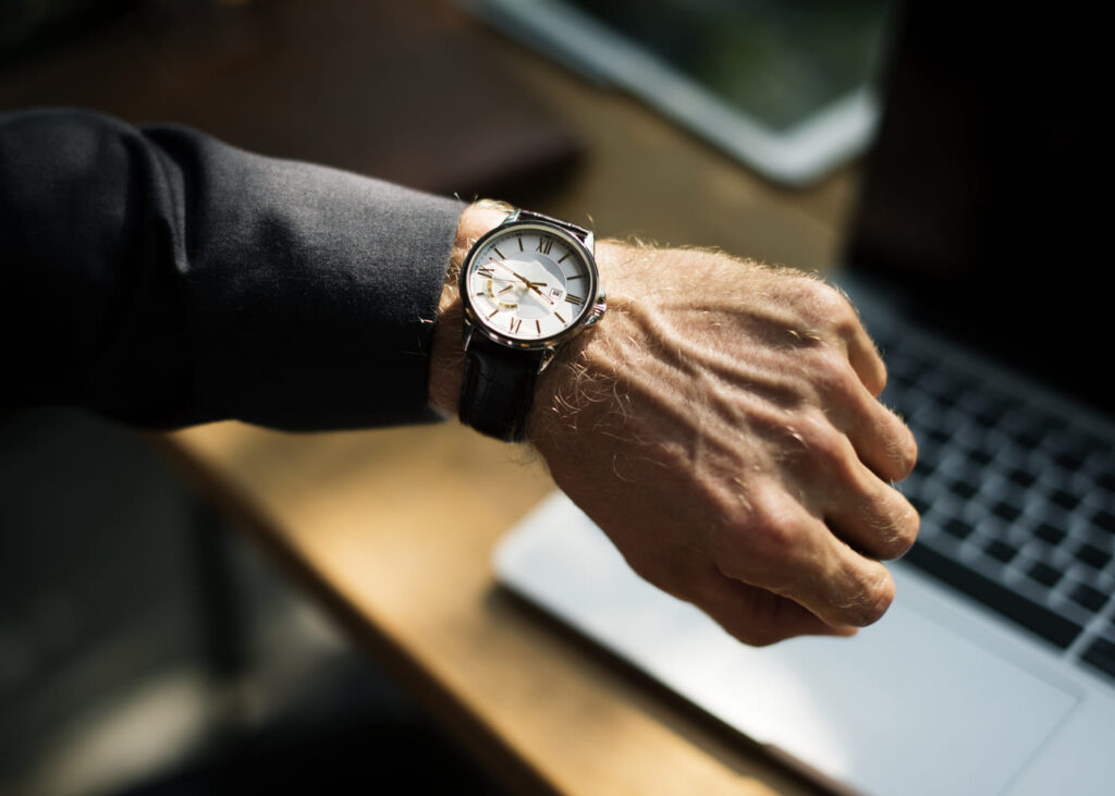 poignet-d-un-homme-qui-porte-une-montre-avec-un-ordinateur-en-fond