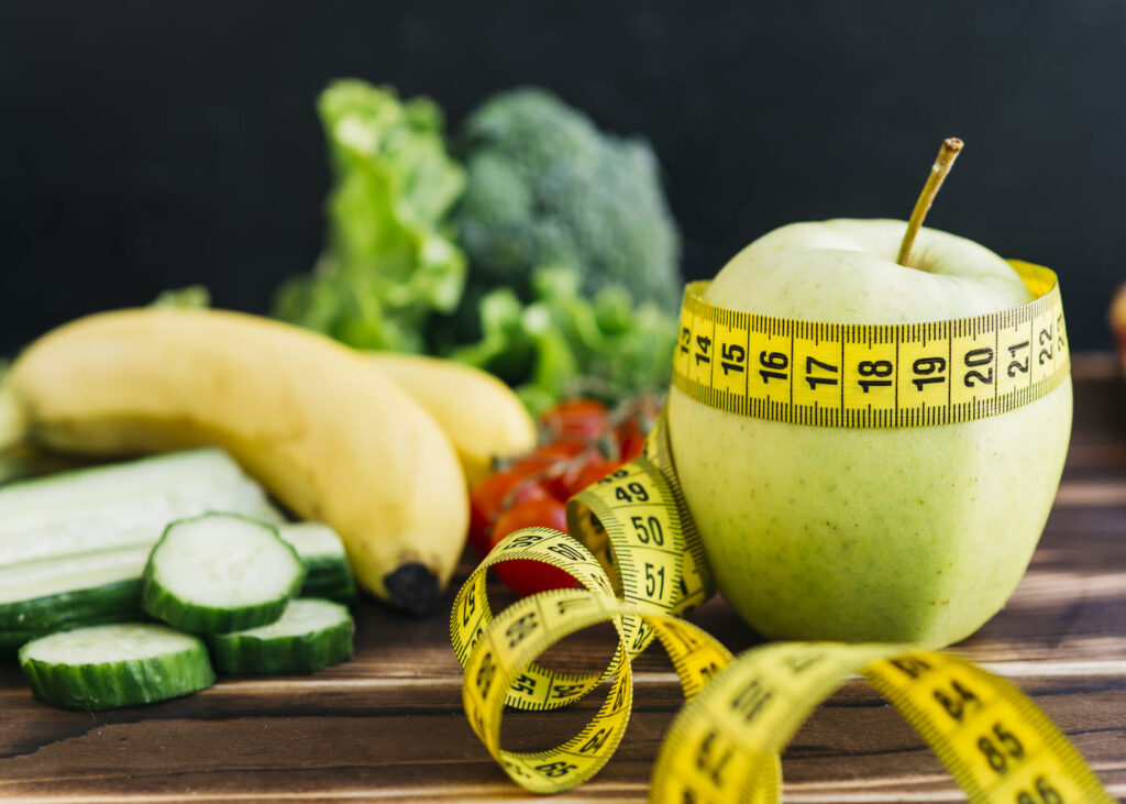 pomme-entouree-d-un-metre-avec-d-autres-fruits-poses-sur-une-table
