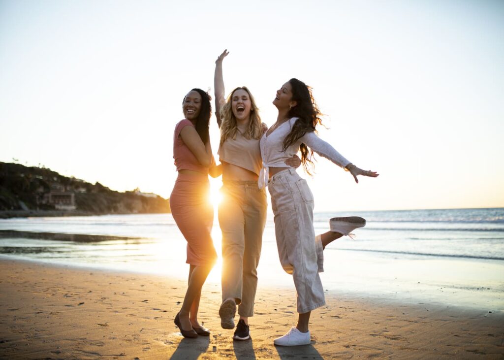 trois-femmes-qui-prennent-la-pose-en-souriant-sur-une-plage-devant-la-mer
