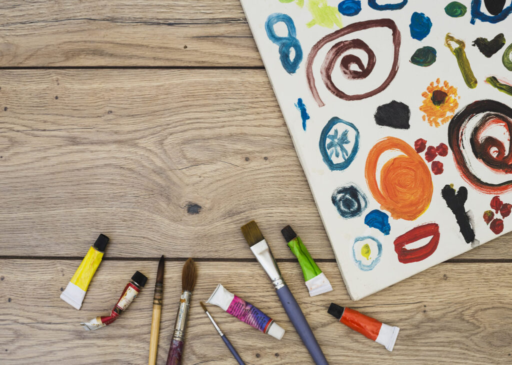vue-de-dessus-de-materiel-artistique-miniature-avec-un-dessin-sur-une-table-en-bois
