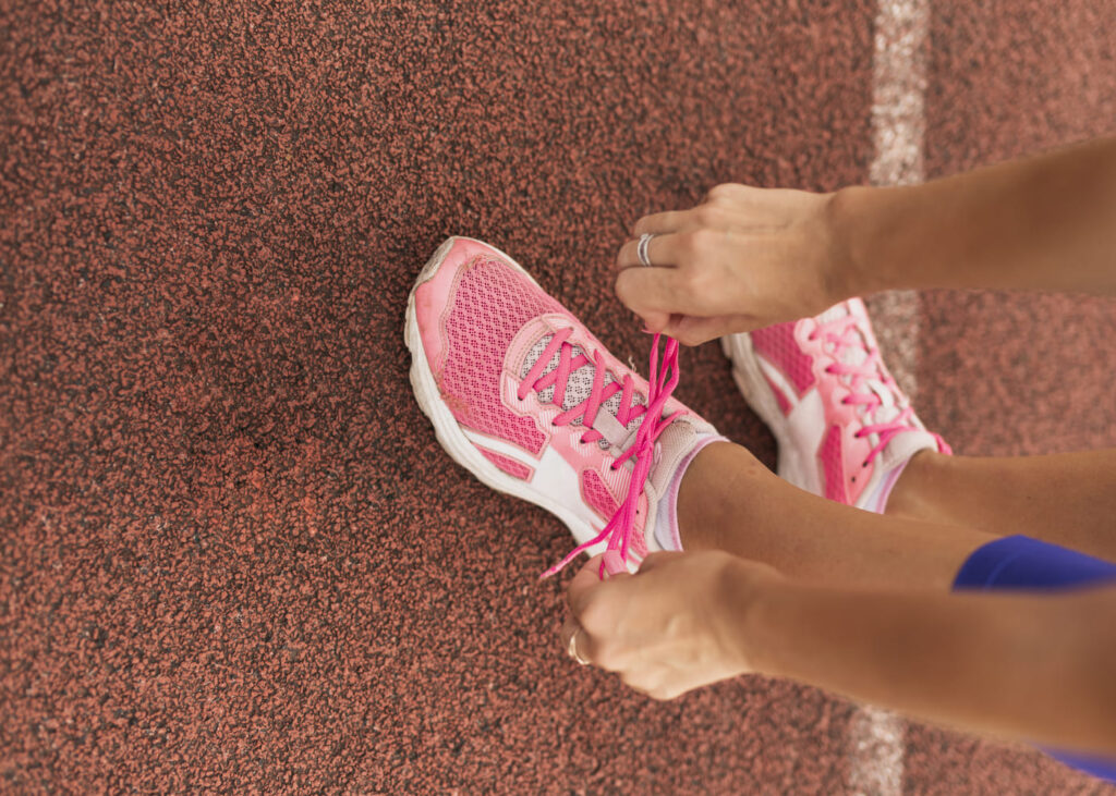 vue-du-dessus-d-une-femme-qui-lace-ses-chaussures-de-running-sur-une-piste