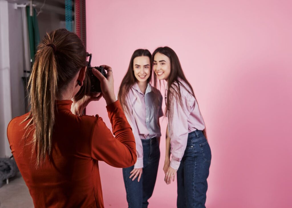 deux-copines-qui-font-un-shooting-photo-avec-une-photographe-et-un-fond-rose