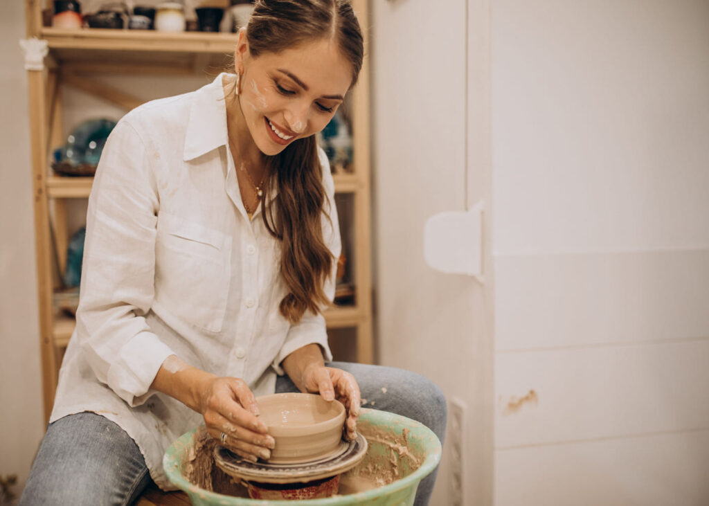 femme-assise-qui-sourit-en-faisant-de-la-poterie