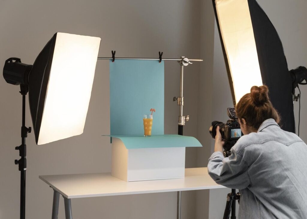 femme-dans-un-studio-photo-qui-photographie-un-verre-sur-fond-bleu
