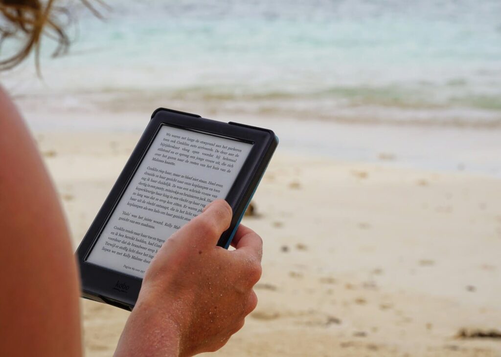 gros-plan-d-une-femme-a-la-plage-qui-lit-sur-une-liseuse