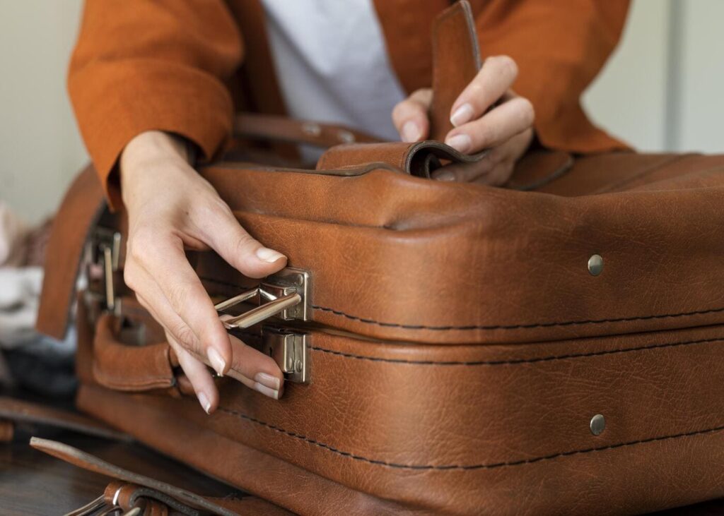 gros-plan-sur-des-mains-de-femme-qui-ferme-une-valise-en-cuir