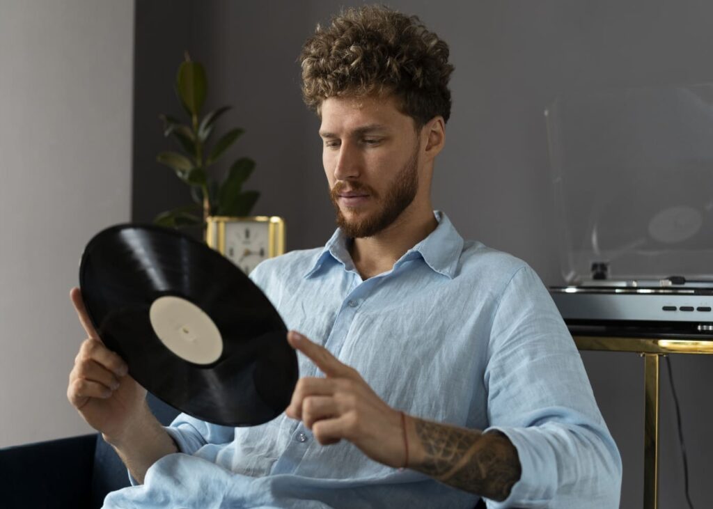 homme-assis-qui-tient-un-vinyle-dans-ses-mains