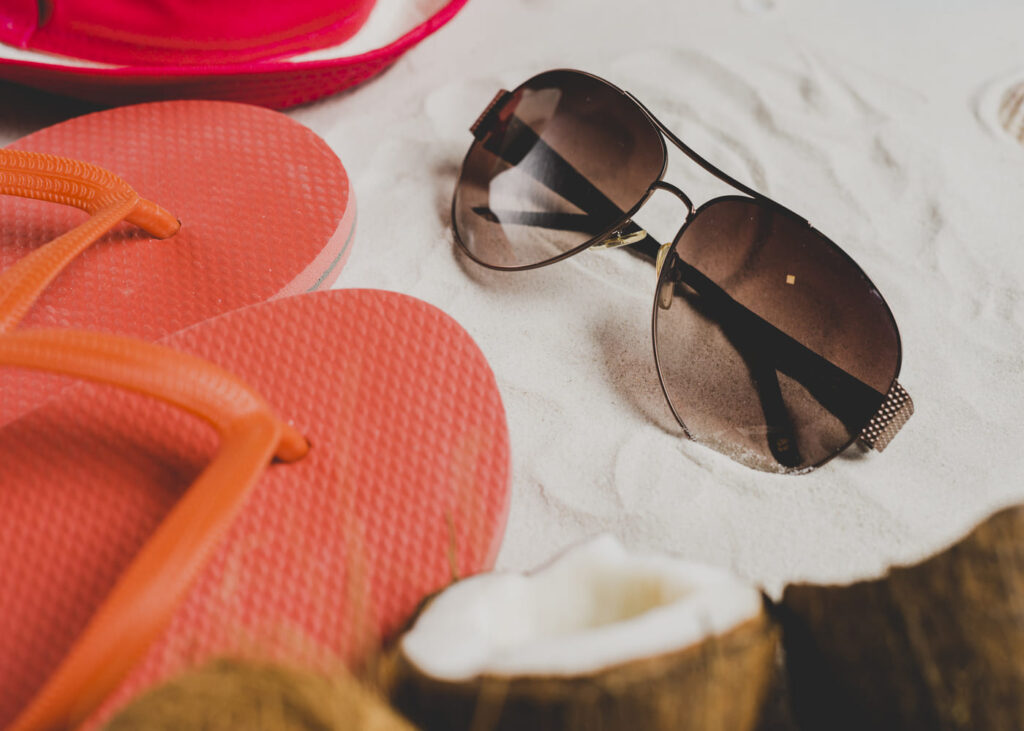 lunettes-de-soleil-poseees-sur-une-serviette-a-cote-de-tongs-roses