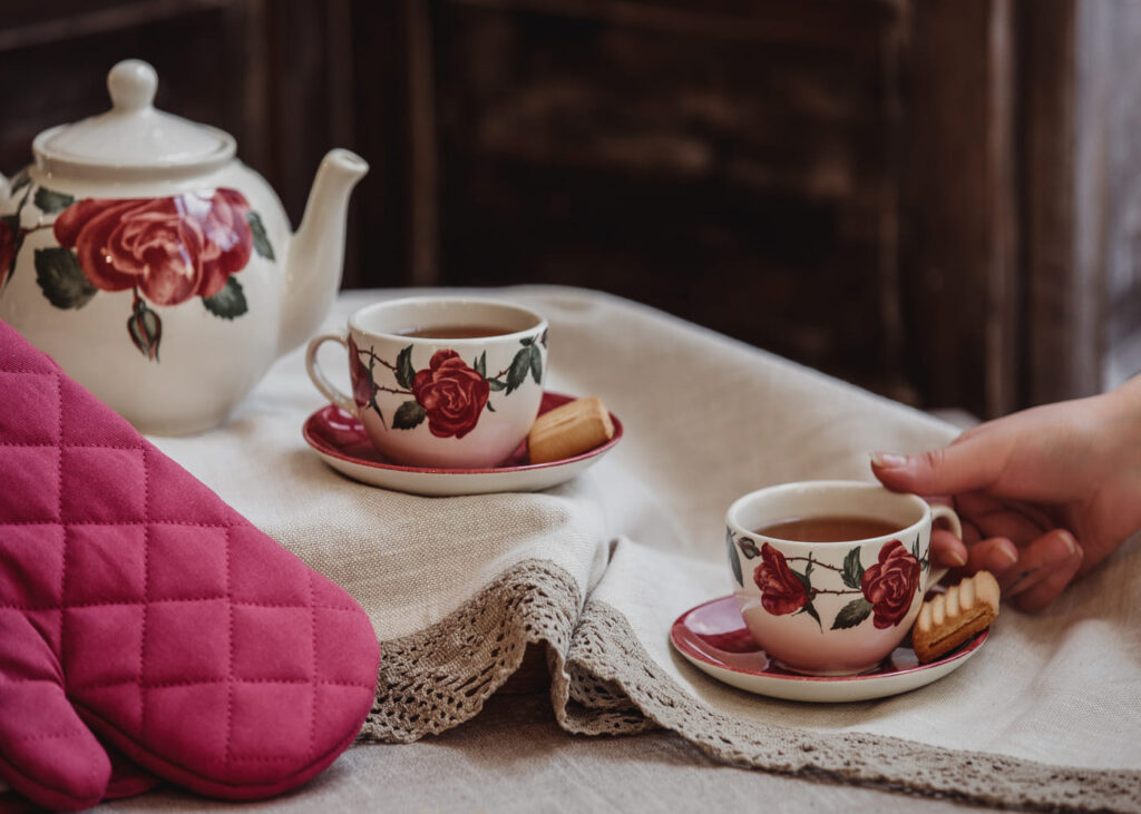 main-d-une-femme-qui-attrappe-une-tasse-avec-service-a-the-avec-des-fleurs-dessus-a-cote