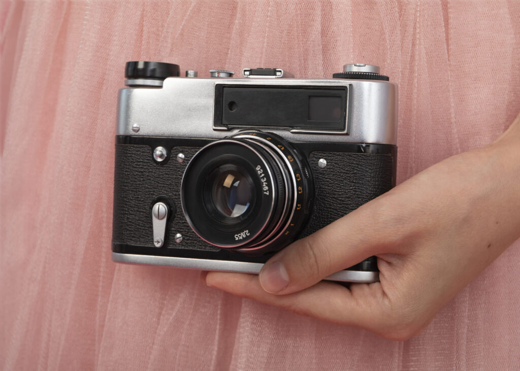 main-de-femme-qui-tient-un-appareil-photo-argentique