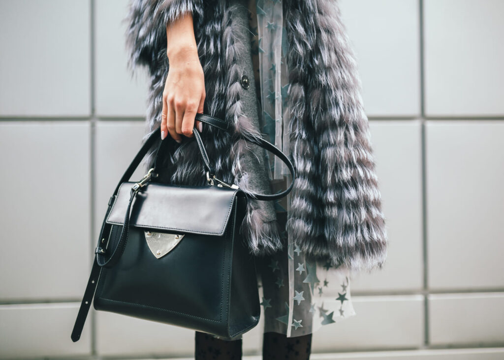 vue-rapprochee-d-une-femme-dans-la-rue-avec-un-manteau-gris-et-qui-tient-un-sac-noir-et-gris-a-la-main