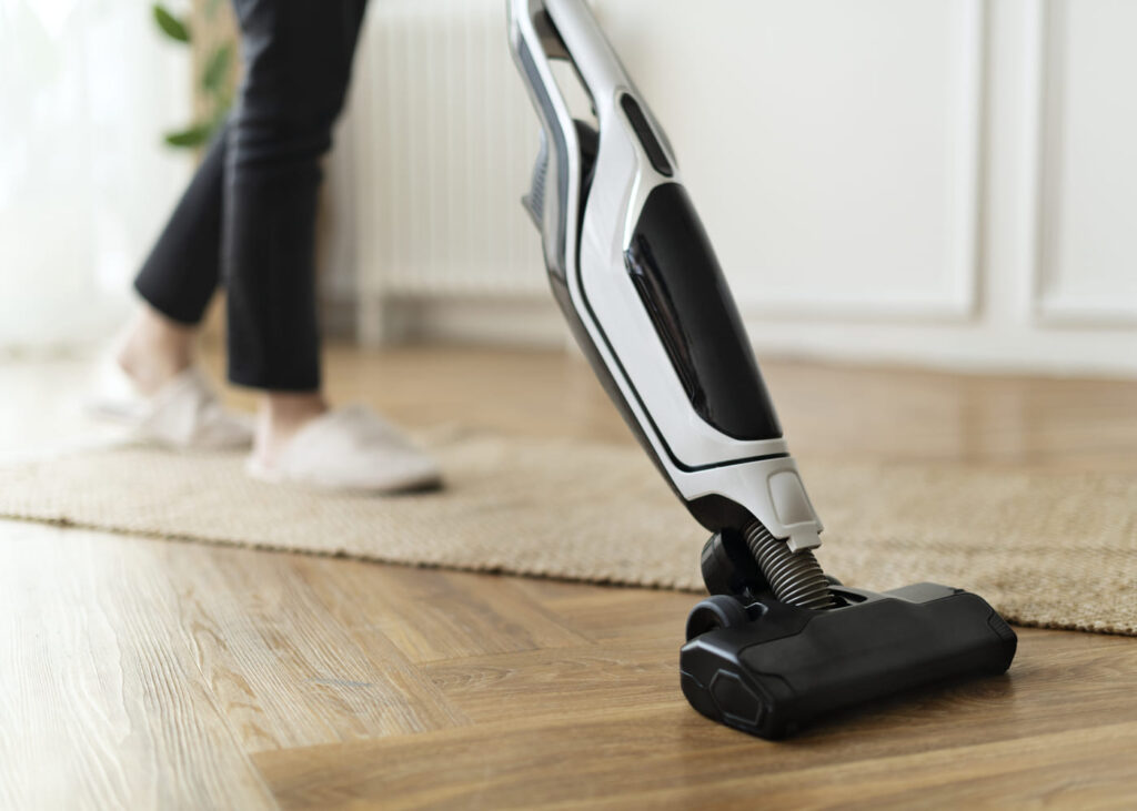 gros-plan-d-une-personne-qui-passe-l-aspirateur-sur-le-parquet-de-sa-maison