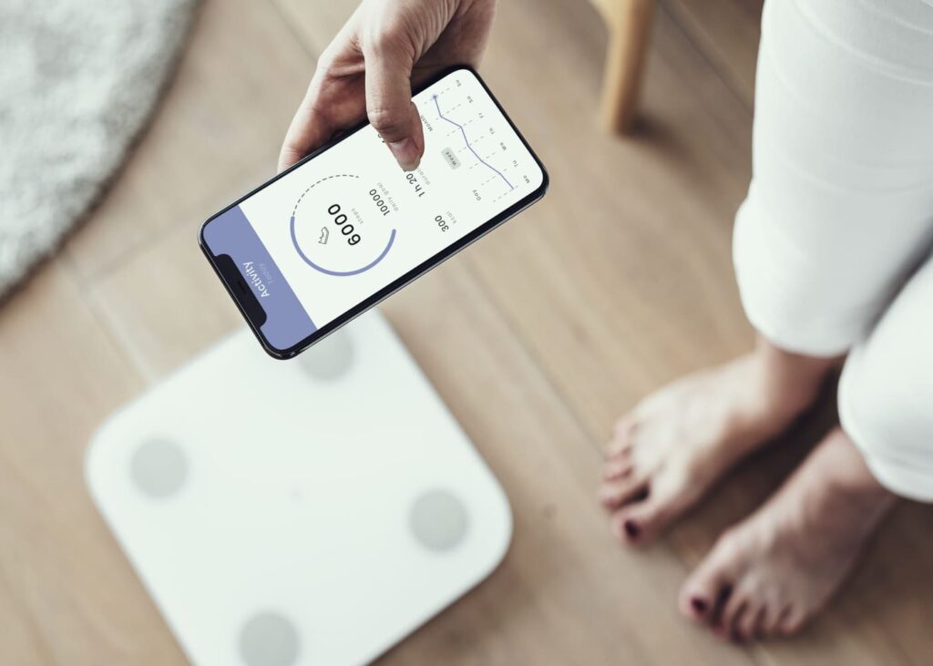 gros-plan-d-une-personne-qui-utilise-une-balance-connectee-avec-son-telephone