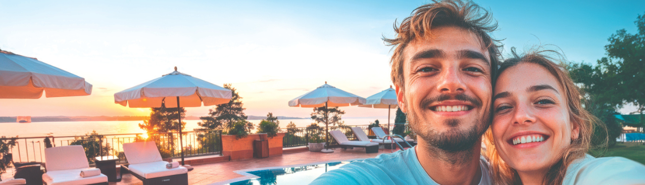 couple heureux en vacances qui prend un selfie devant une piscine